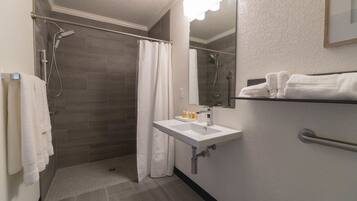 Een badkamer met een douche, een wastafel en een spiegel.