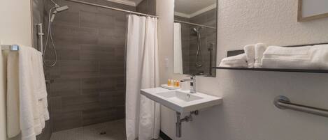 Un bagno con doccia, lavandino e specchio.