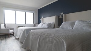 A hotel room with two beds, a chair, a large window, and a wall clock. - Lakeside Inn (Clear Lake)