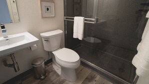 A bathroom with a white sink, toilet, and glass-enclosed shower. - Lakeside Inn (Clear Lake)