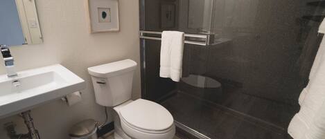 A bathroom with a white sink, toilet, and glass-enclosed shower.