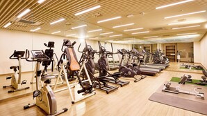 A gym with various exercise machines, wooden floors, and a mirrored wall. - Hotel Thomas Myeongdong (Seoul)