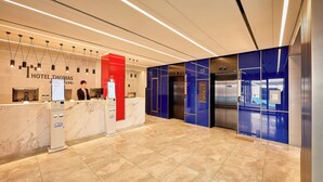 A modern hotel lobby with a reception desk, elevators, and a marble floor. - Hotel Thomas Myeongdong (Seoul)