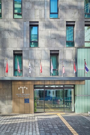 A hotel facade with multiple windows, flags, and a sign reading "HOTEL THOMAS MYEONG DONG". - Hotel Thomas Myeongdong (Seoul)