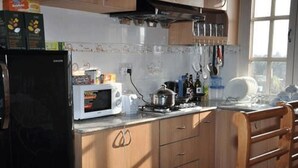 A kitchen with wooden cabinets, a microwave, and various kitchen items on the counter. - Bliss Apartment (Kathmandu)