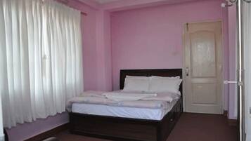 Un dormitorio con una cama individual, una puerta y una ventana con cortinas.