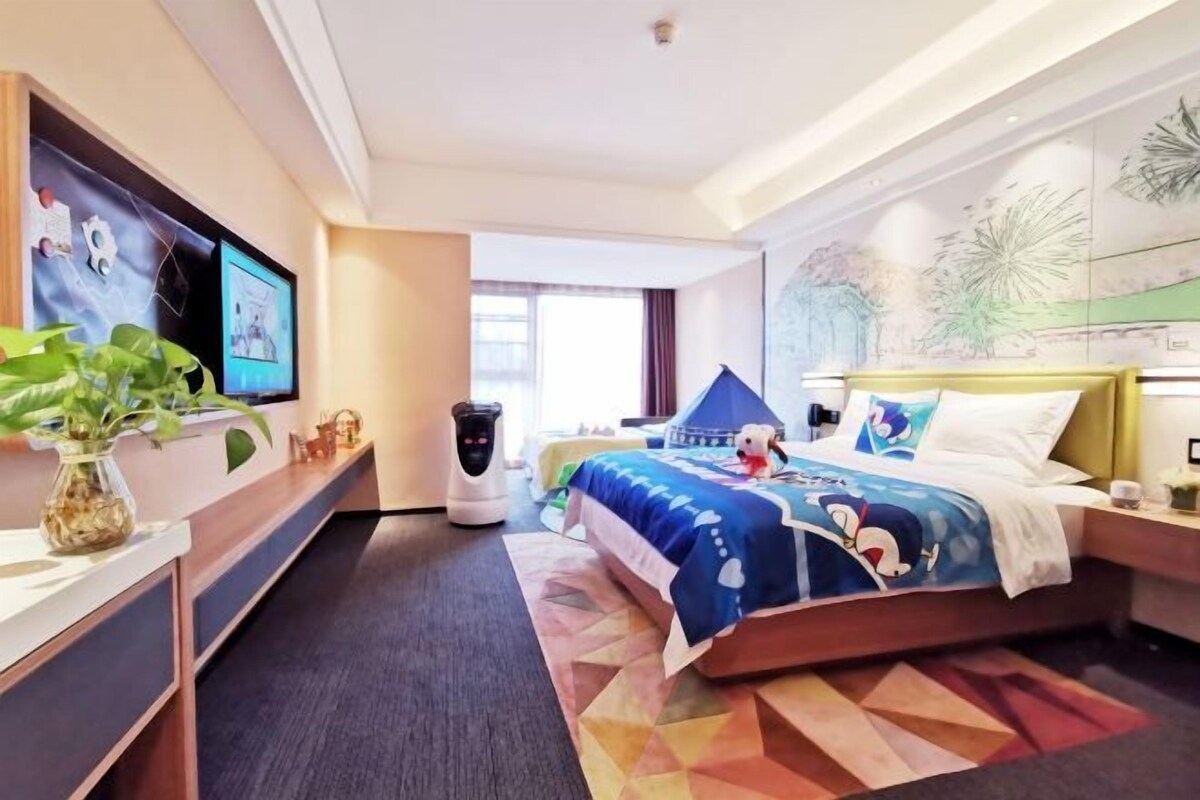 A hotel room with a bed, a TV, a coffee maker, and a plant.