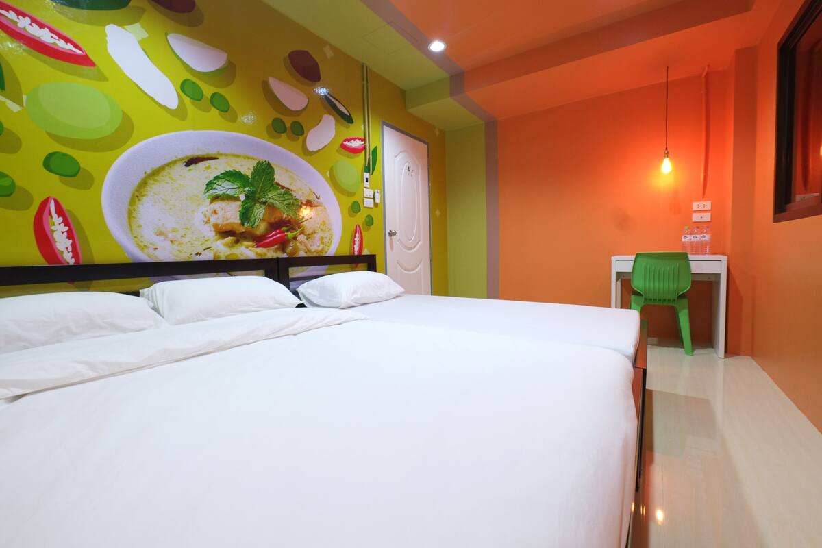 Une chambre d’hôtel avec un grand lit, un bureau avec une chaise et une fresque murale.