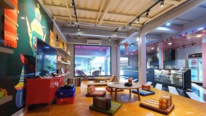 Un intérieur moderne avec un plancher en bois, des sièges aux couleurs vives, un piano rouge et une grande fenêtre donnant sur l’extérieur.