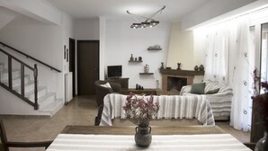 A living room with a fireplace, a sofa, a coffee table, and a staircase. - Villa Jasmine (Agios Vasileios)