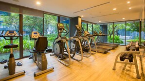 A gym with treadmills, elliptical machines, and weight benches. - The Deck Condo Patong by VIP (Patong)