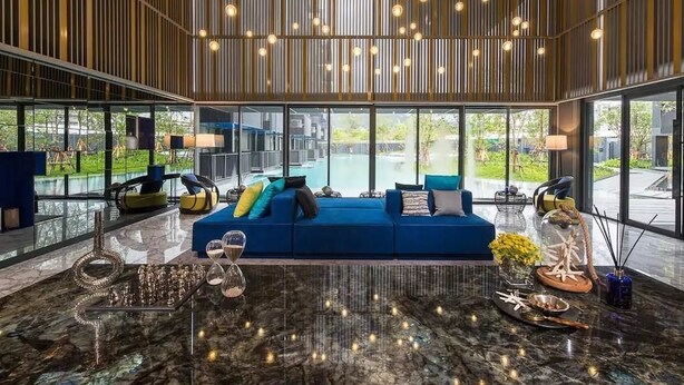 A modern living room with a blue sofa, a glass coffee table, and a decorative sculpture. - The Deck Condo Patong by VIP (Patong)