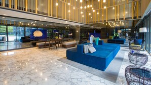 A spacious lobby with a blue sofa, seating area, and a high ceiling with hanging lights. - The Deck Condo Patong by VIP (Patong)