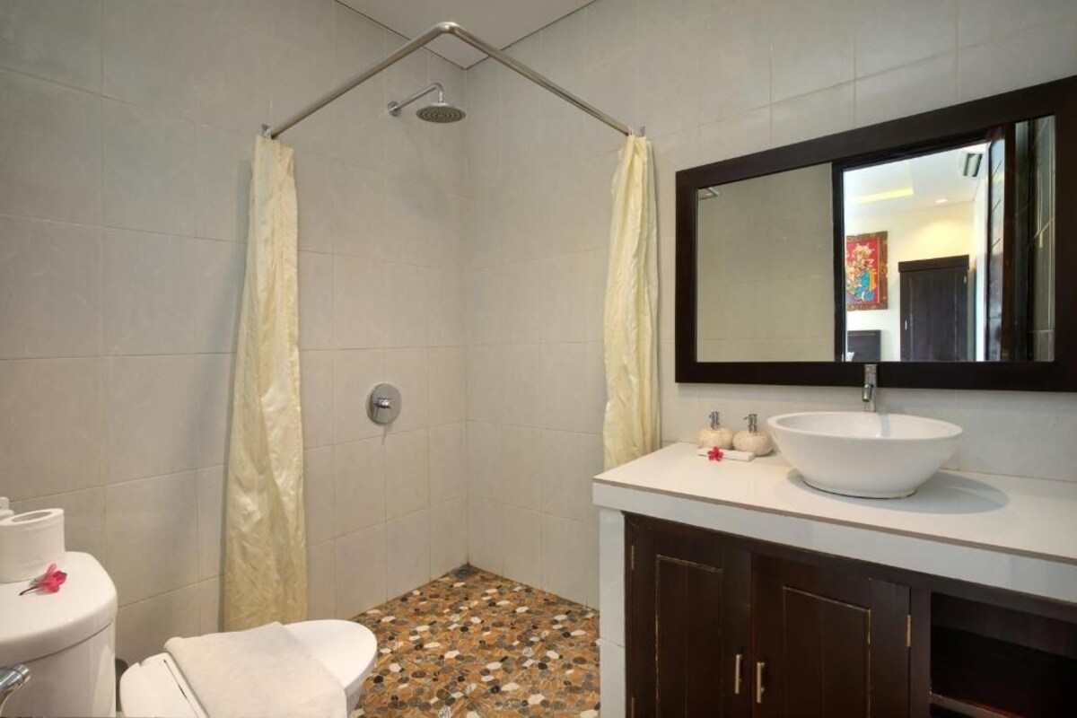 Un baño con ducha, inodoro, lavabo y espejo.