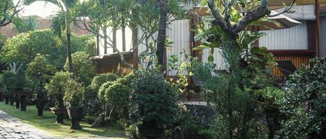 A pathway lined with potted plants leading to a building with a tiled roof.