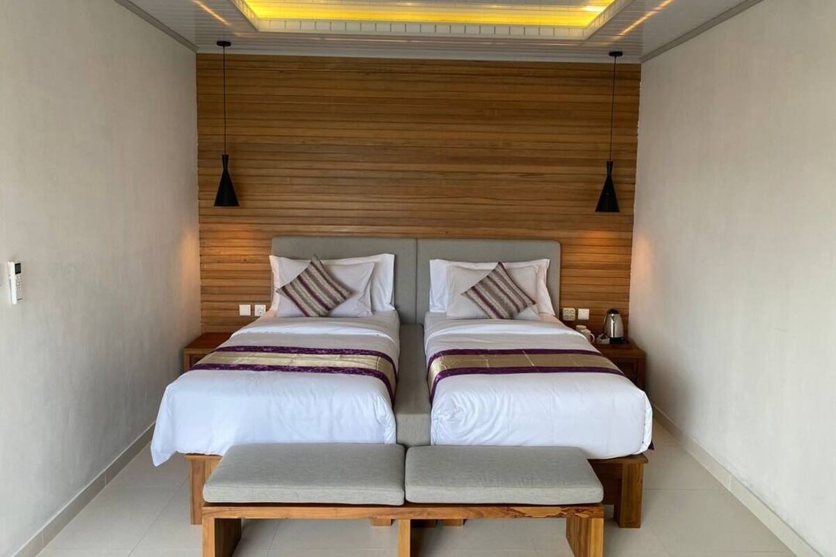 A double bed with two nightstands, a bench, and a wooden headboard.