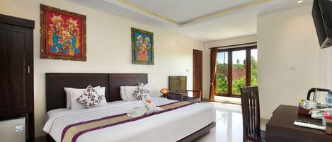 A hotel room with a large bed, a dining table, a TV, and artwork on the walls.