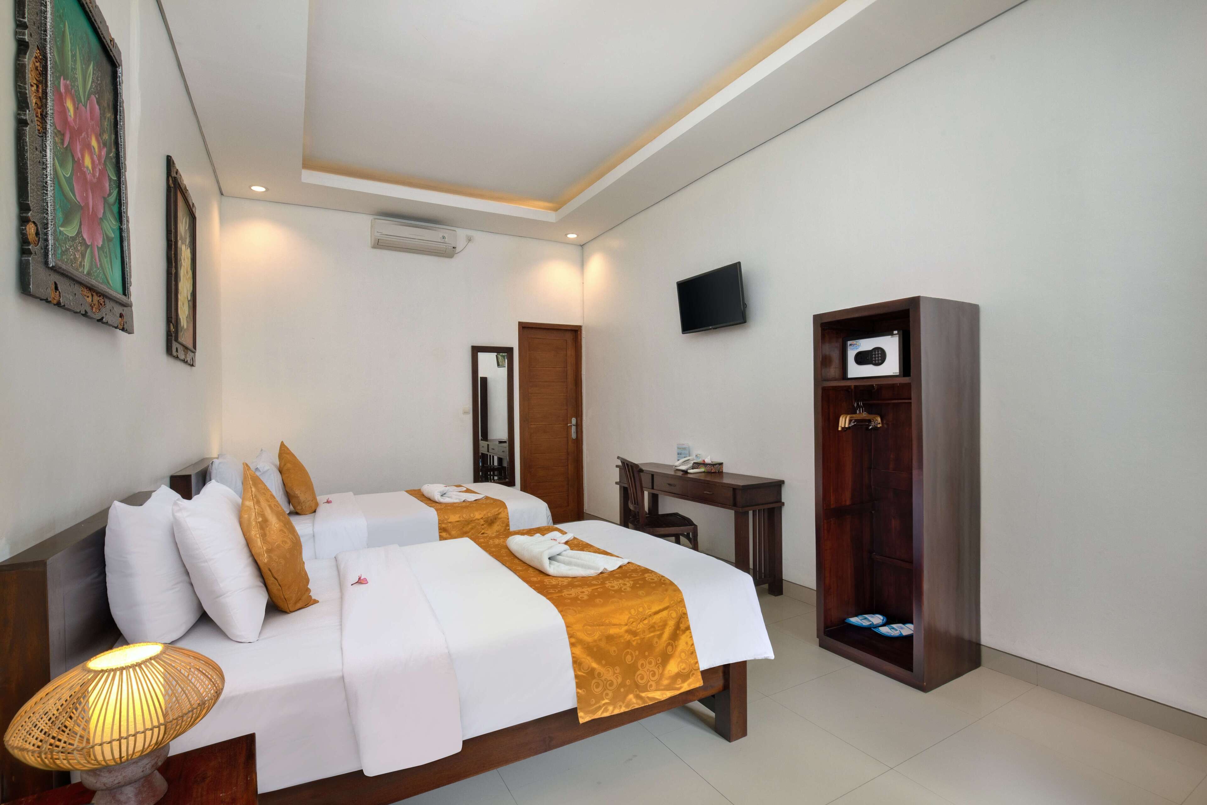 Habitación de hotel con dos camas, un escritorio, un televisor y un armario.