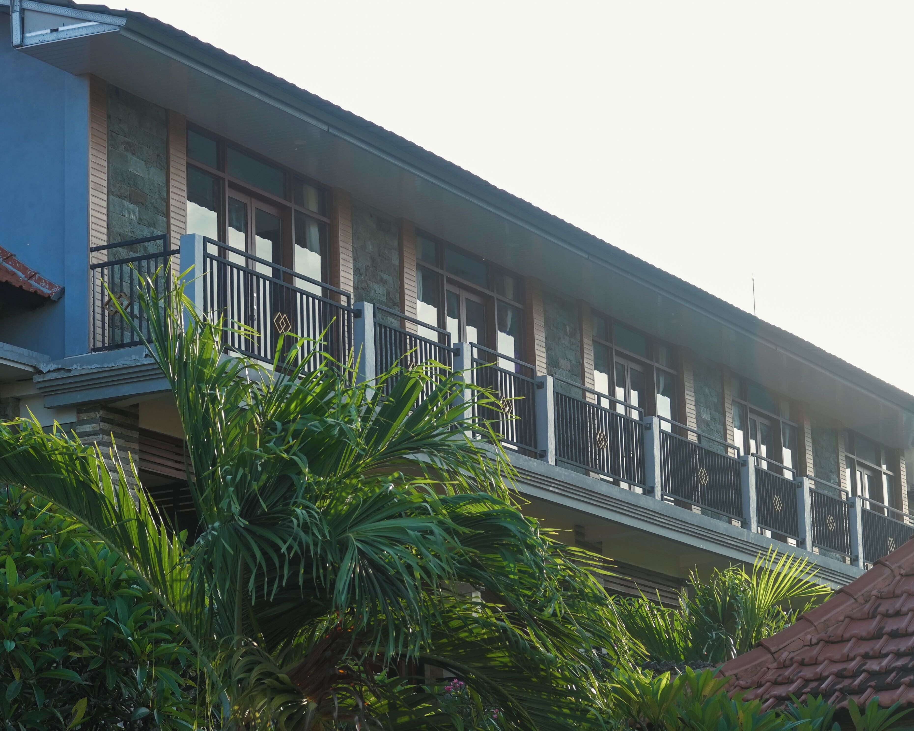 A multi-story building with balconies, surrounded by lush greenery.