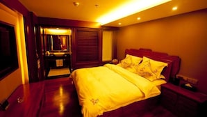A bedroom with a large bed, wooden flooring, a nightstand, and a mirror. - Lijiang Taohuadao Post Inn (Lijiang)