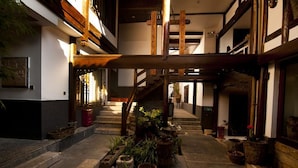 A traditional Japanese building with a wooden staircase, potted plants, and a stone floor. - Lijiang Taohuadao Post Inn (Lijiang)