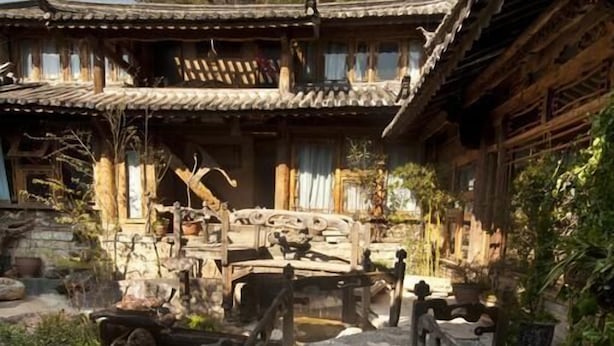 A traditional courtyard with a stone pathway leading to a wooden gate. - Lijiang Taohuadao Post Inn (Lijiang)