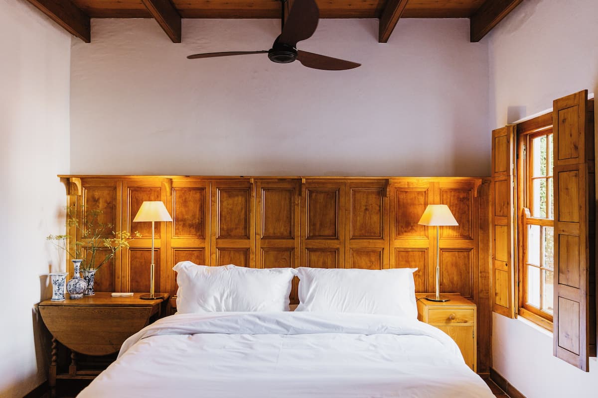 Ein Schlafzimmer mit einem Holz-Kopfteil, zwei Nachttischen mit Lampen und einem Deckenventilator.