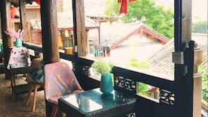 An outdoor seating area with wicker furniture and a view of traditional buildings. - Lijiang Shanju Zuihuayin Inn (Lijiang)