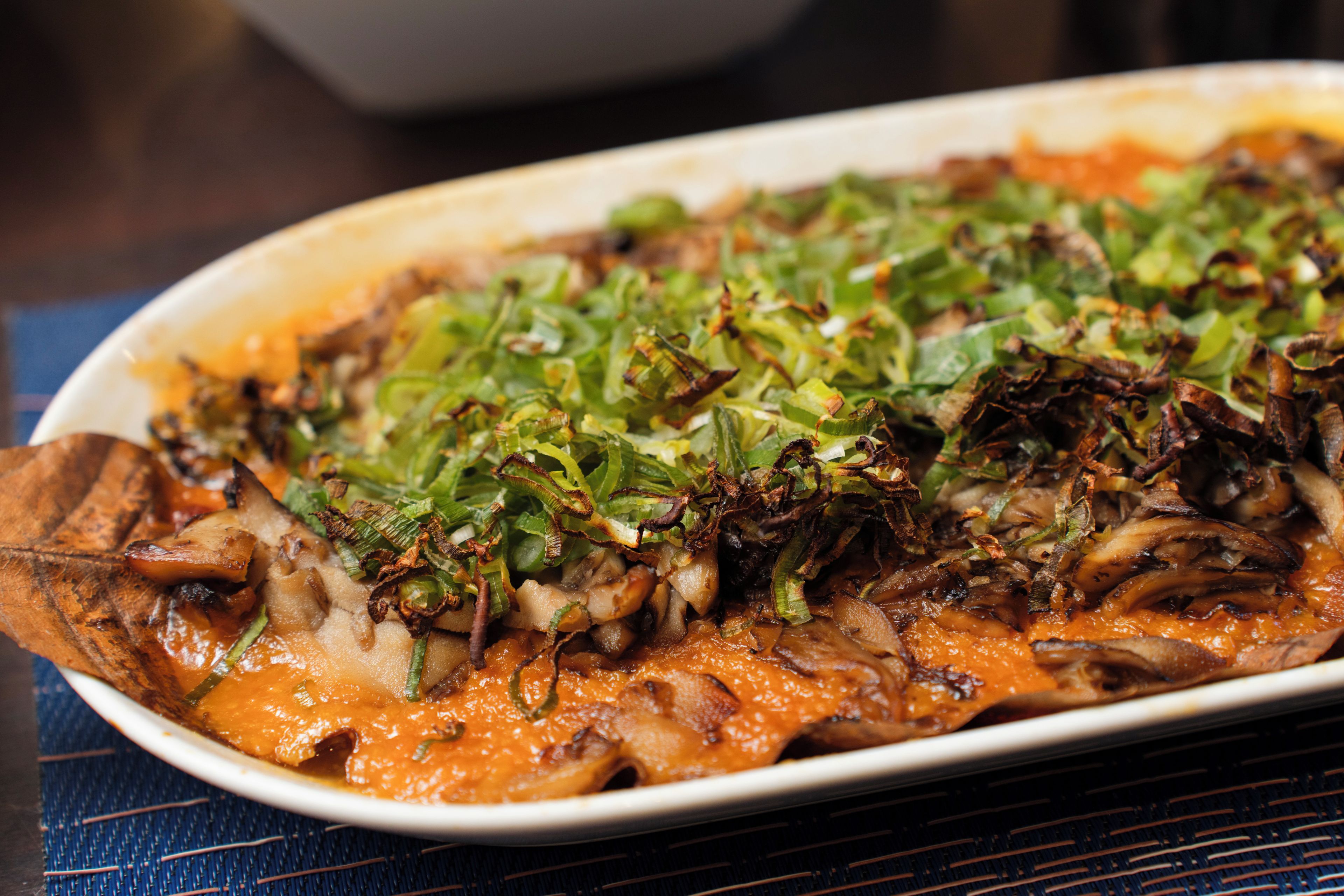 A dish with mushrooms and greens on a white plate.