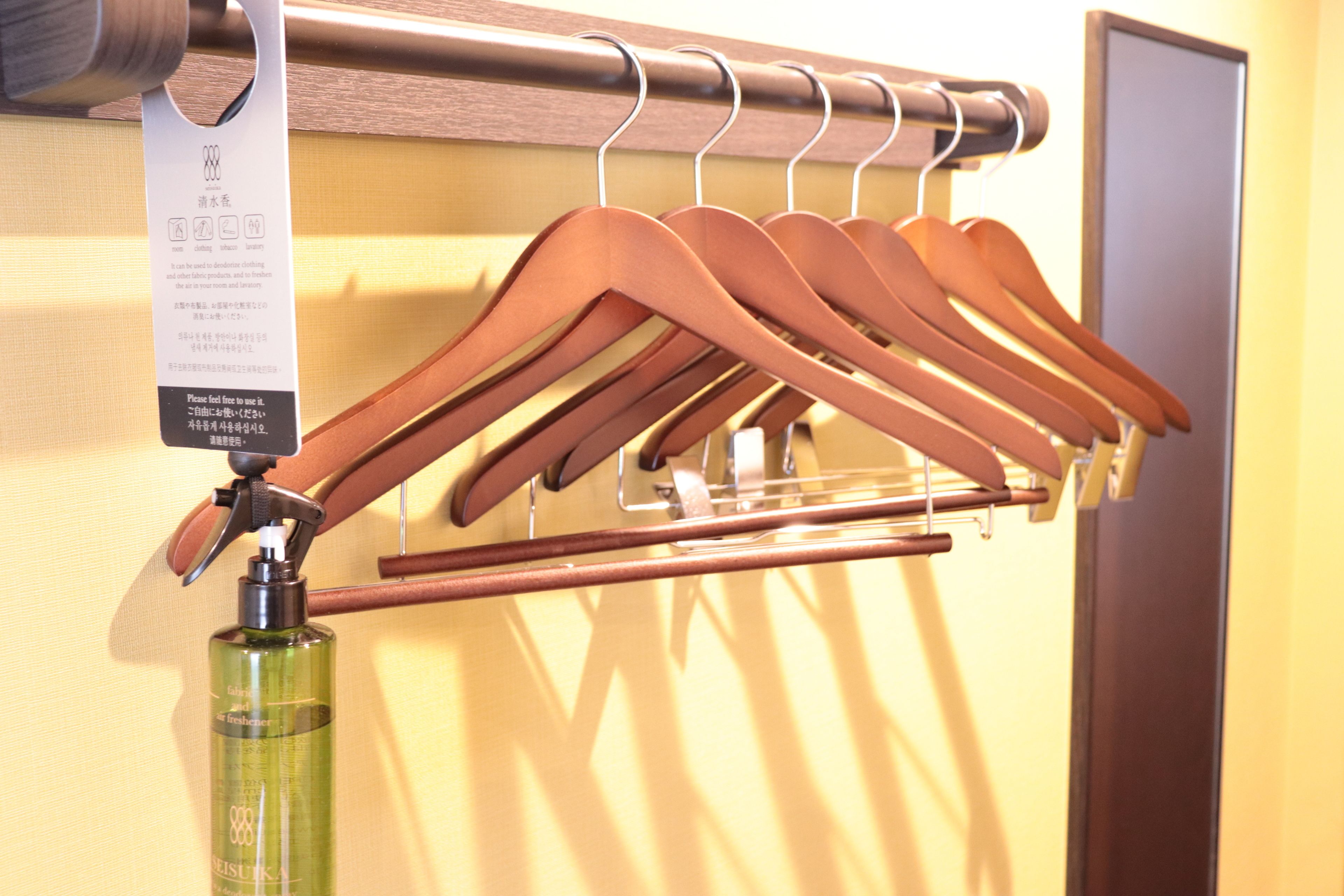A rack of wooden hangers and a spray bottle on a wall.
