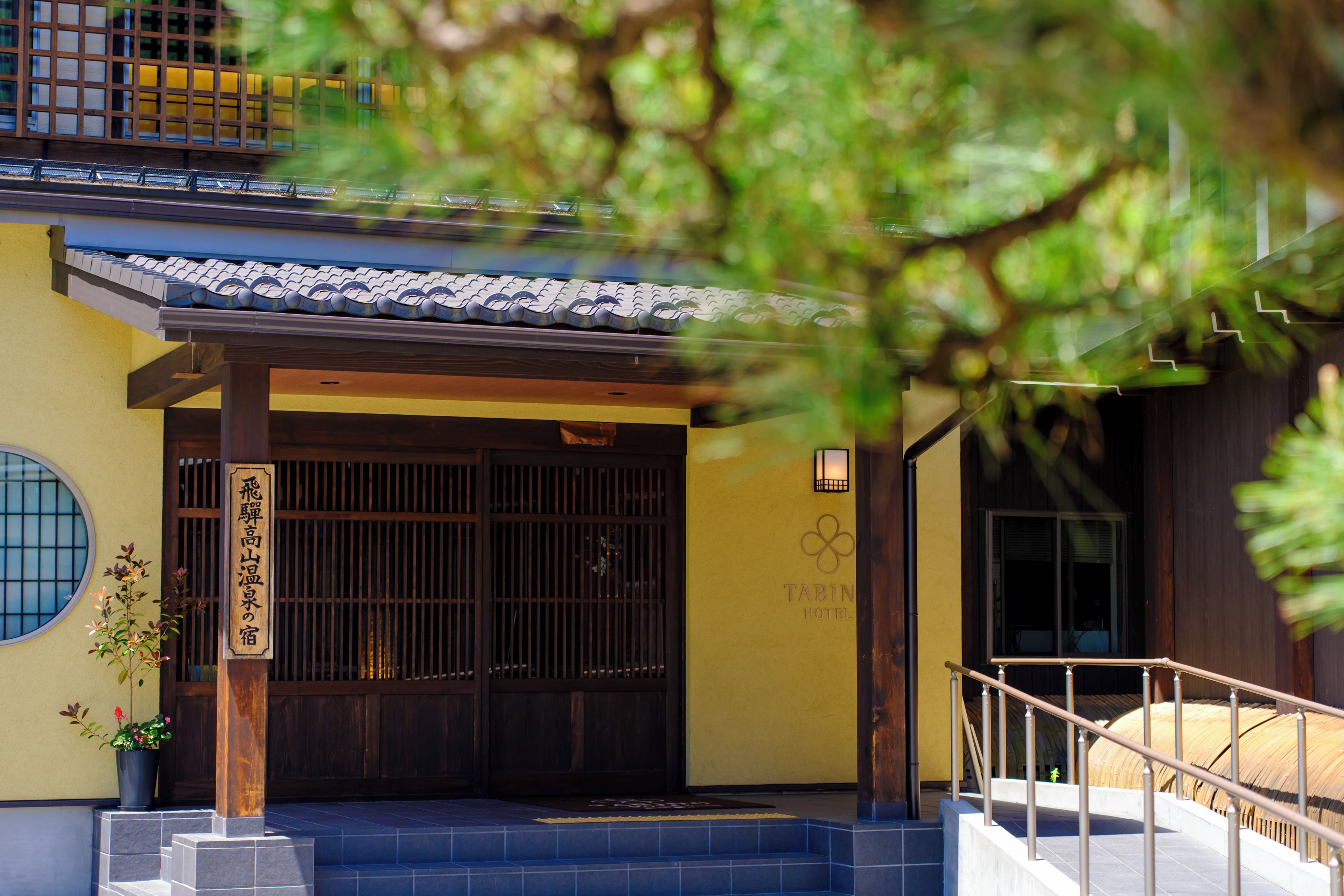 Un edificio japonés tradicional con entrada de madera, techo de tejas y un letrero que indica el nombre del negocio.