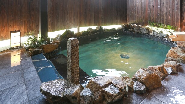 A hot tub surrounded by rocks and a wooden fence. - Tabino Hotel Hida - Takayama (Takayama)