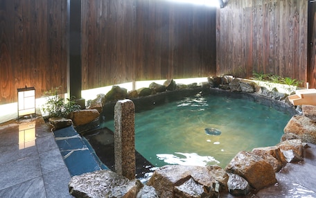 A hot tub surrounded by rocks and a wooden fence.