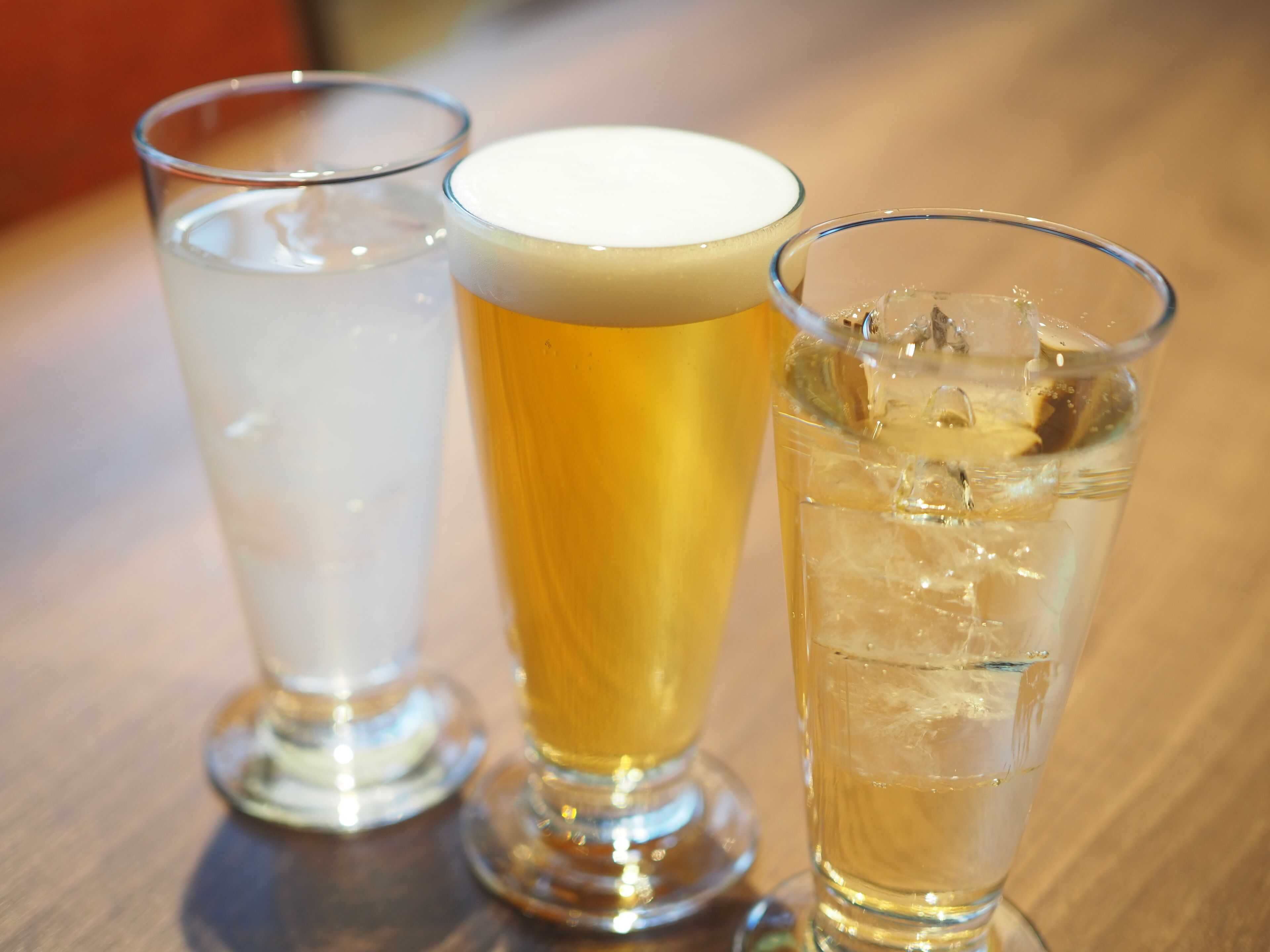 Tres vasos de cerveza sobre una mesa de madera.