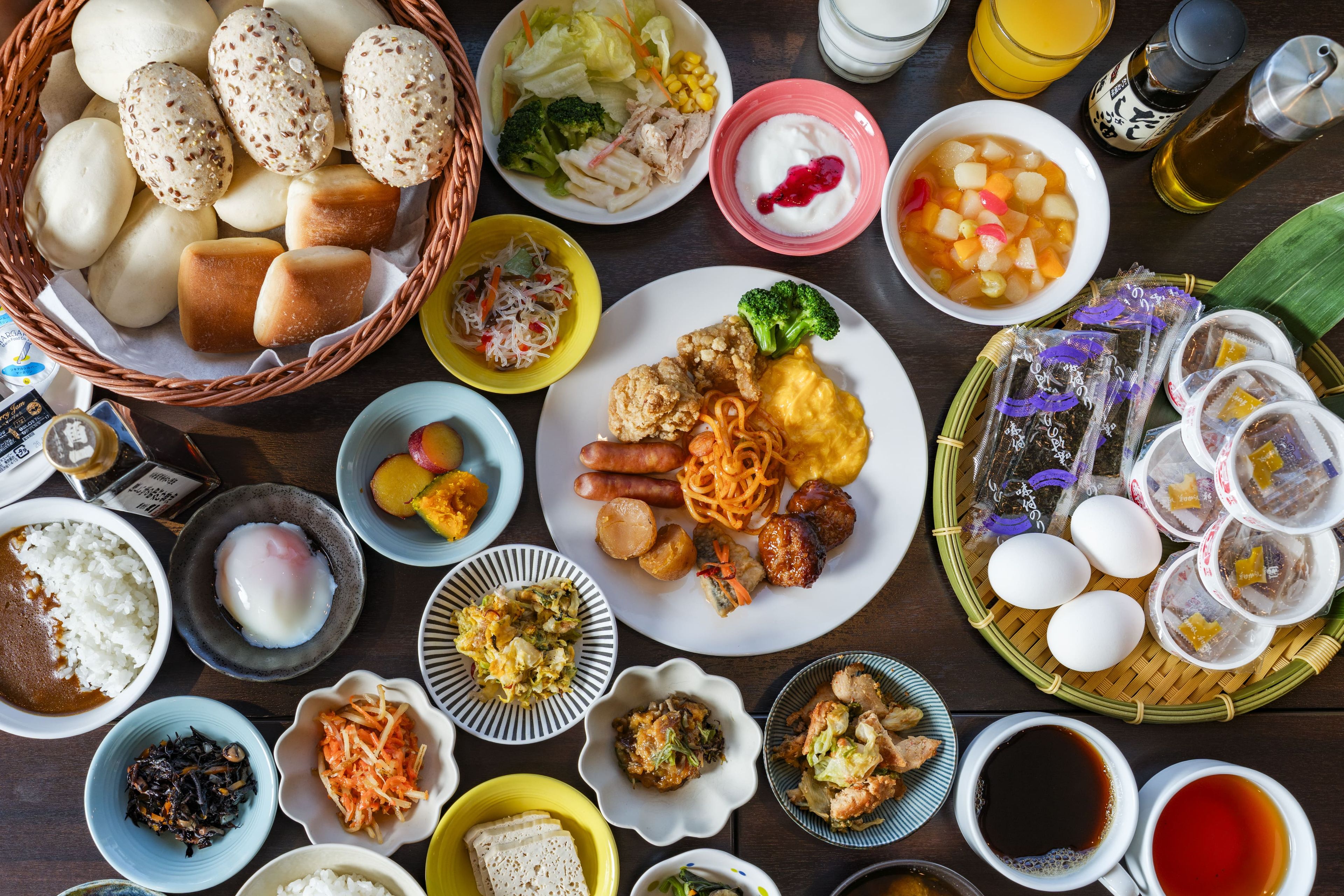 Diversos pratos e alimentos dispostos sobre uma mesa, incluindo arroz, macarrão e acompanhamentos variados.