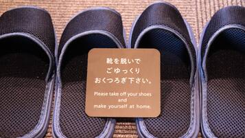A pair of black slippers with a sign instructing to remove shoes and make oneself at home.
