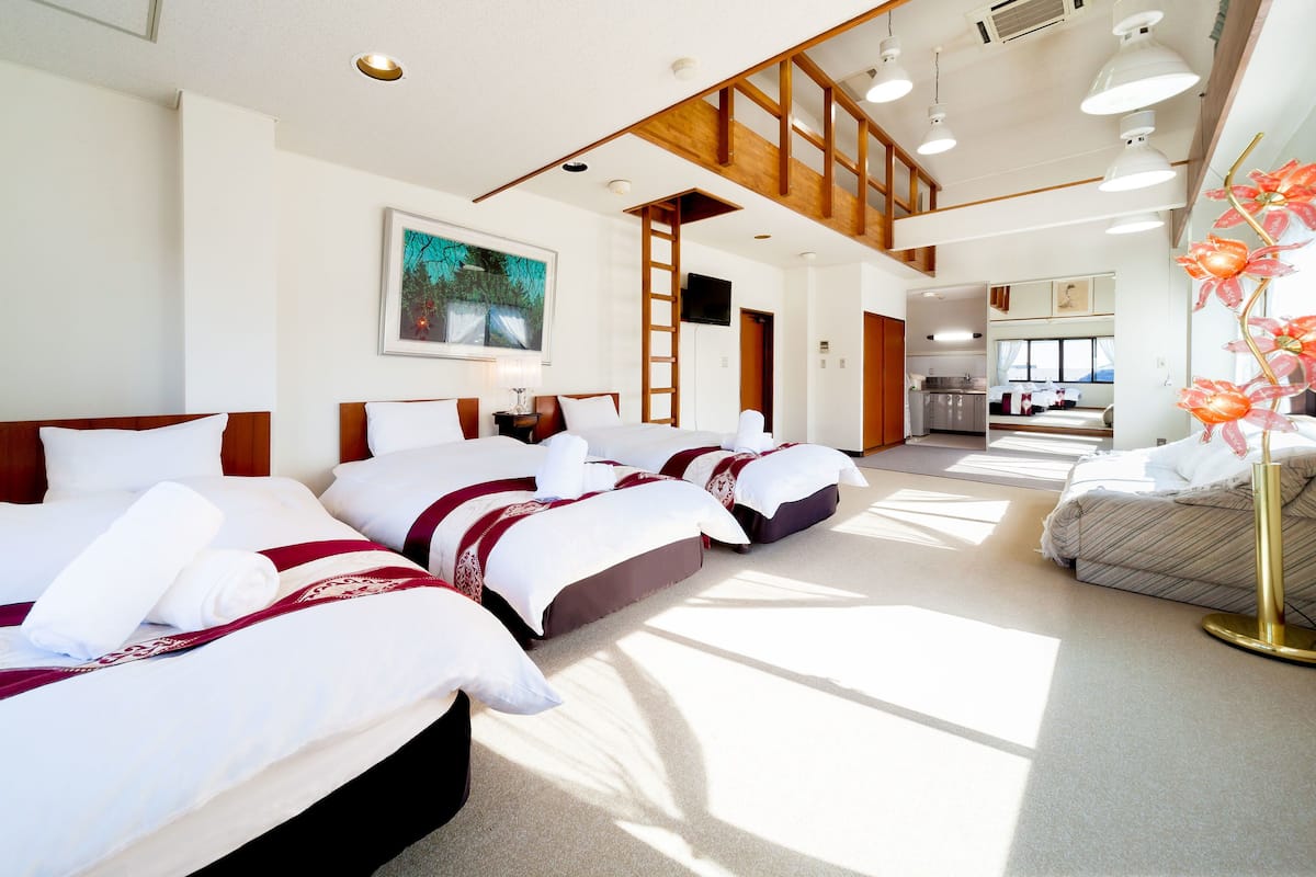 A hotel room with a large bed, a desk, and a view of the kitchen.