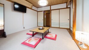 A traditional Japanese room with tatami flooring, a low table, and sliding doors. - Petit Hotel P-Bow (Hakuba)