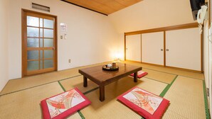 A traditional Japanese room with tatami flooring, a low wooden table, sliding doors, and a ceiling light. - Petit Hotel P-Bow (Hakuba)