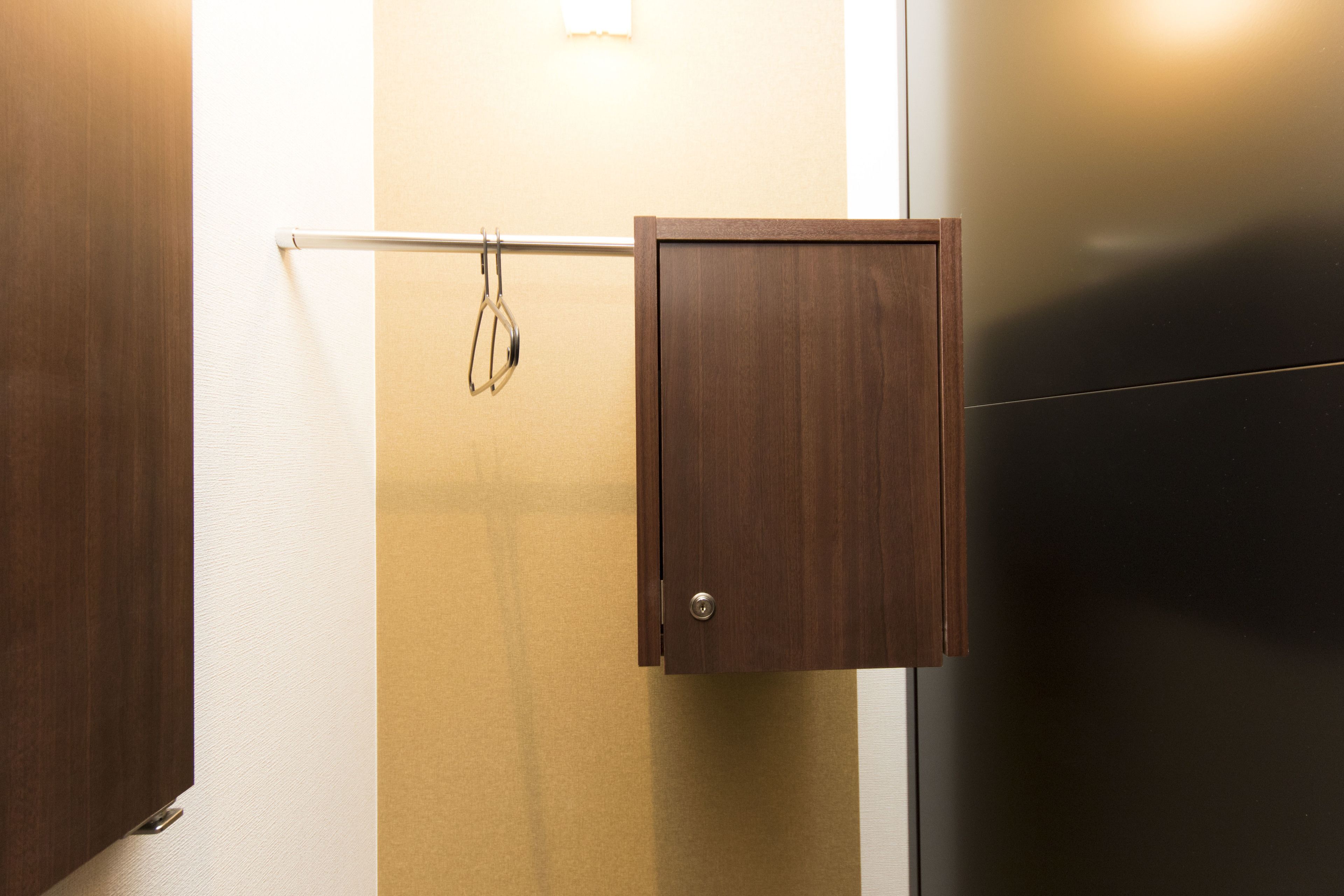 A wooden cabinet with a metal handle, a towel rack, and a door.