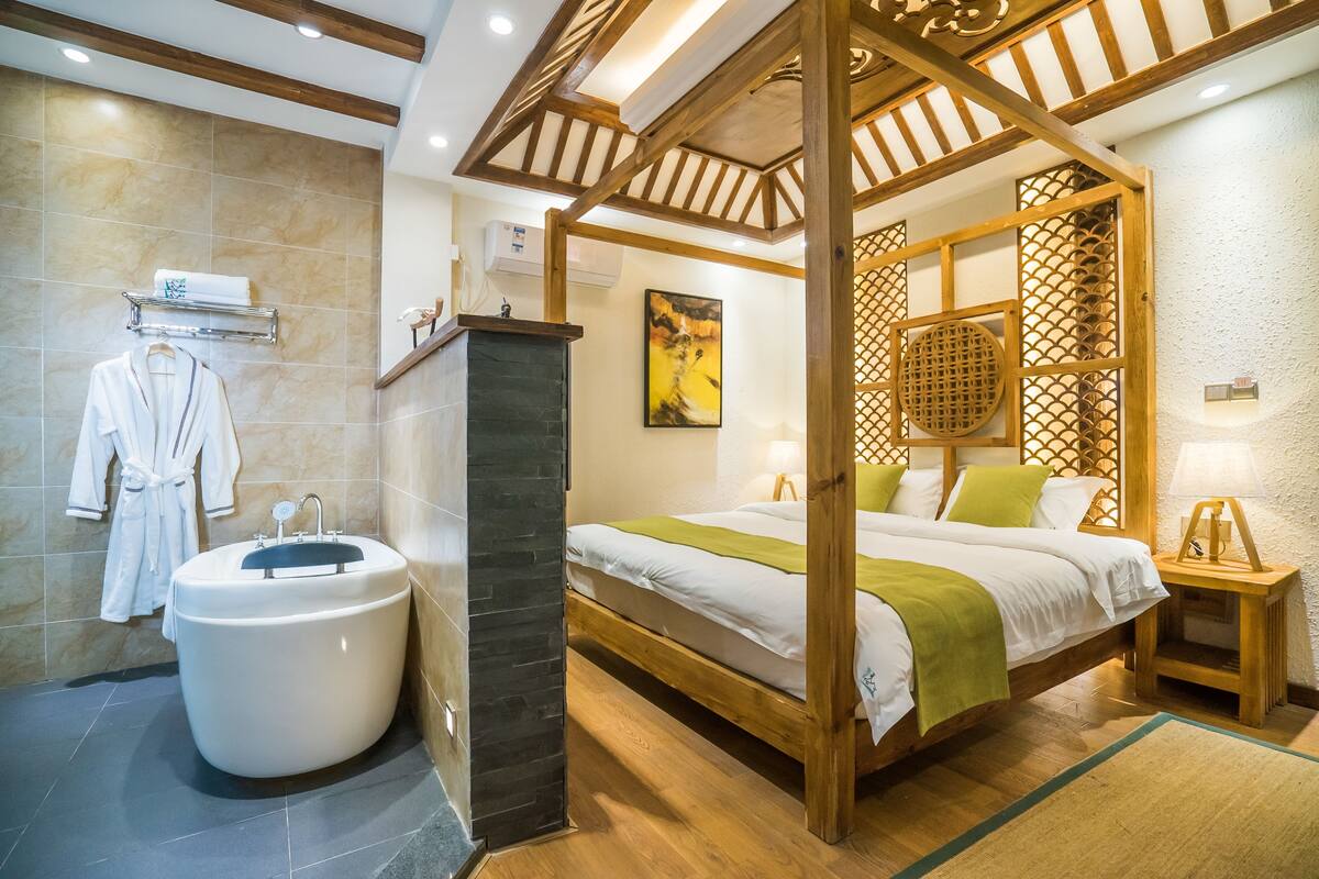 A modern bathroom with a bathtub, a wooden bed with a canopy, and a wooden floor.