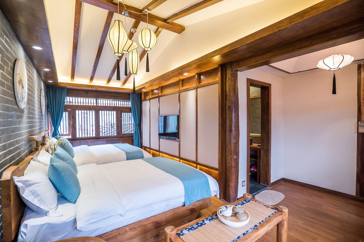 A hotel room with a wooden bed, a small table with a tray, and traditional lanterns hanging from the ceiling.