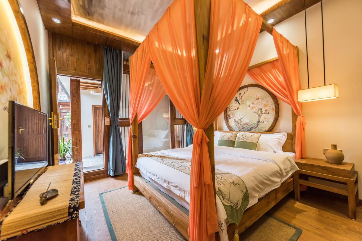 A traditional Japanese-style bedroom with a four-poster bed, wooden flooring, and a large window with curtains.