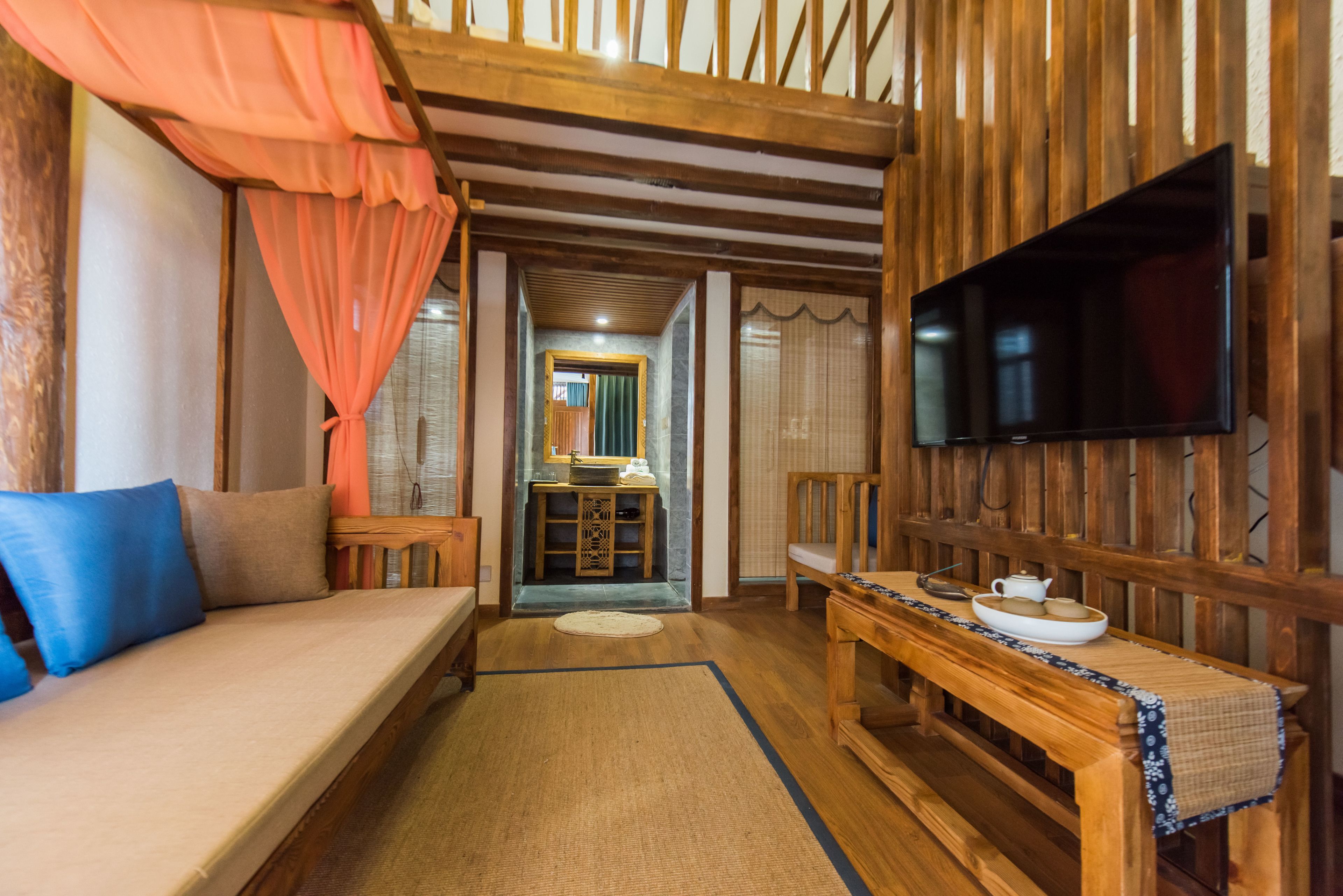 Una habitación acogedora con sofá, banco de madera, televisión y una mesita con tazón y tetera.