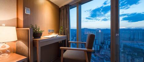 Una habitación moderna con escritorio, silla y ventana grande con vistas a la ciudad.