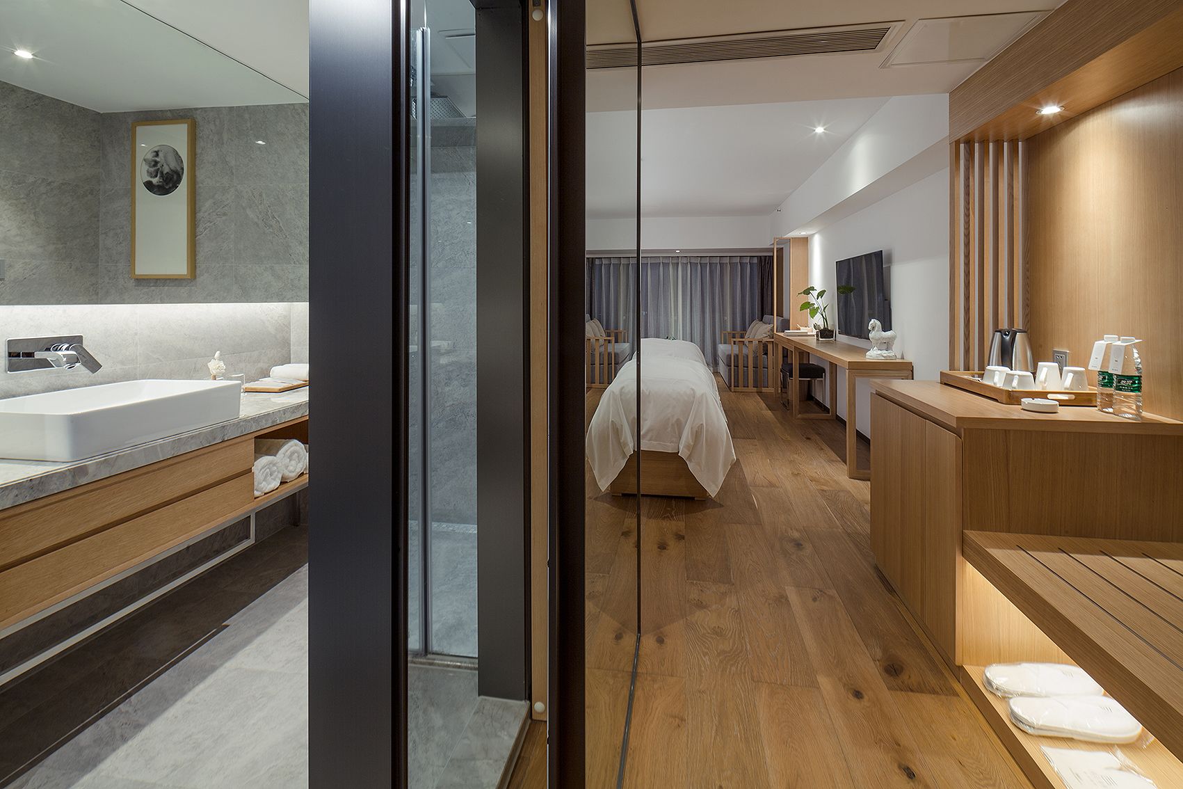 Une chambre d’hôtel moderne dotée d’une grande salle de bain, d’un bureau en bois, d’un lit et d’un téléviseur.
