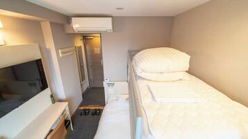 A small, clean room with a bed, a desk, a chair, and a TV.