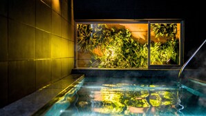 Uma banheira de hidromassagem com vista para vegetação exuberante e uma parede revestida de azulejos.