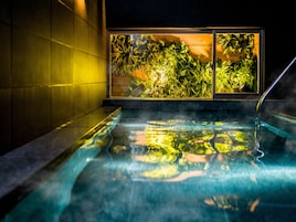 A hot tub with a view of lush greenery and a tiled wall.