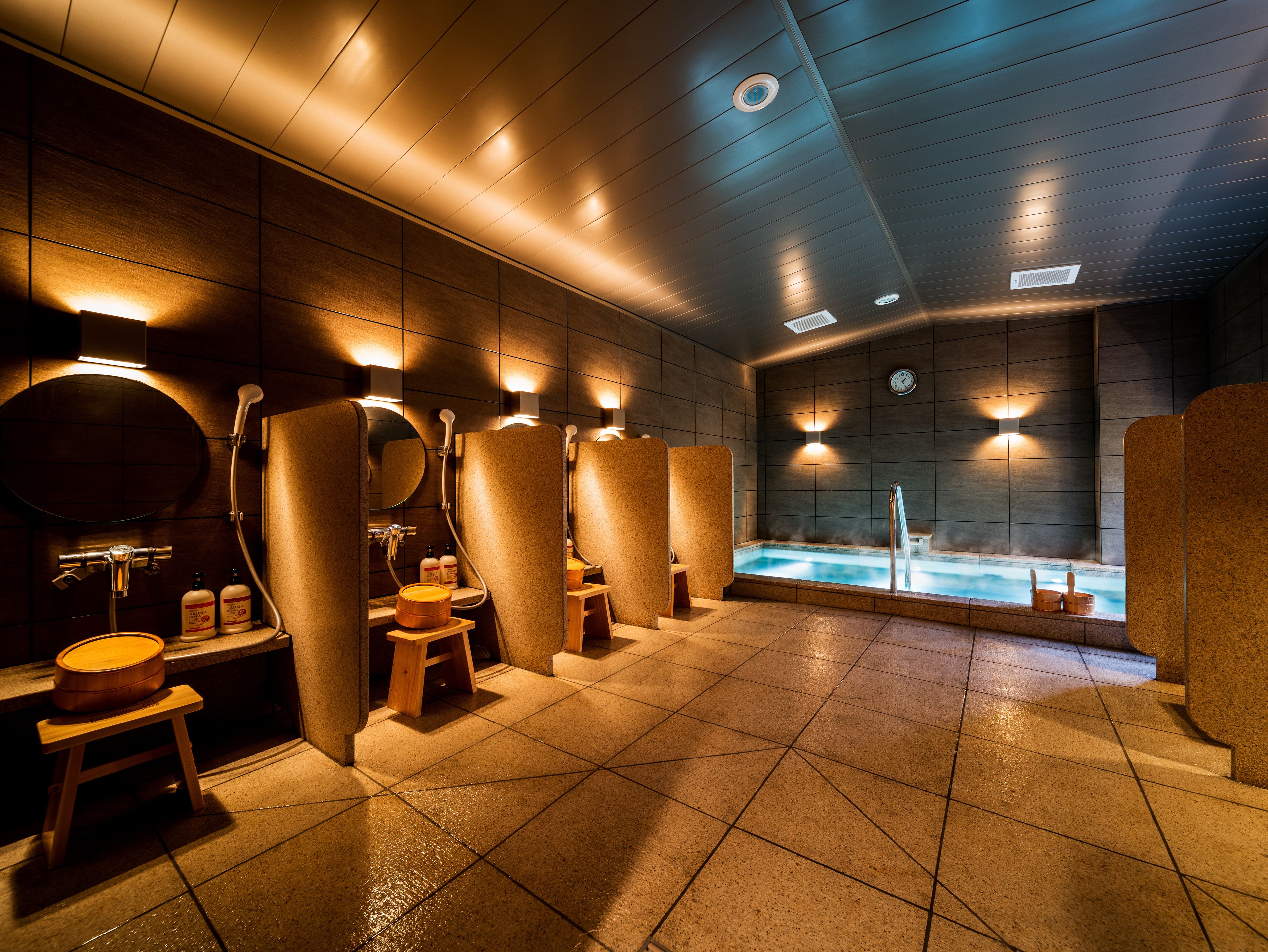A modern spa with individual shower stalls, a central hot tub, and a tiled floor.